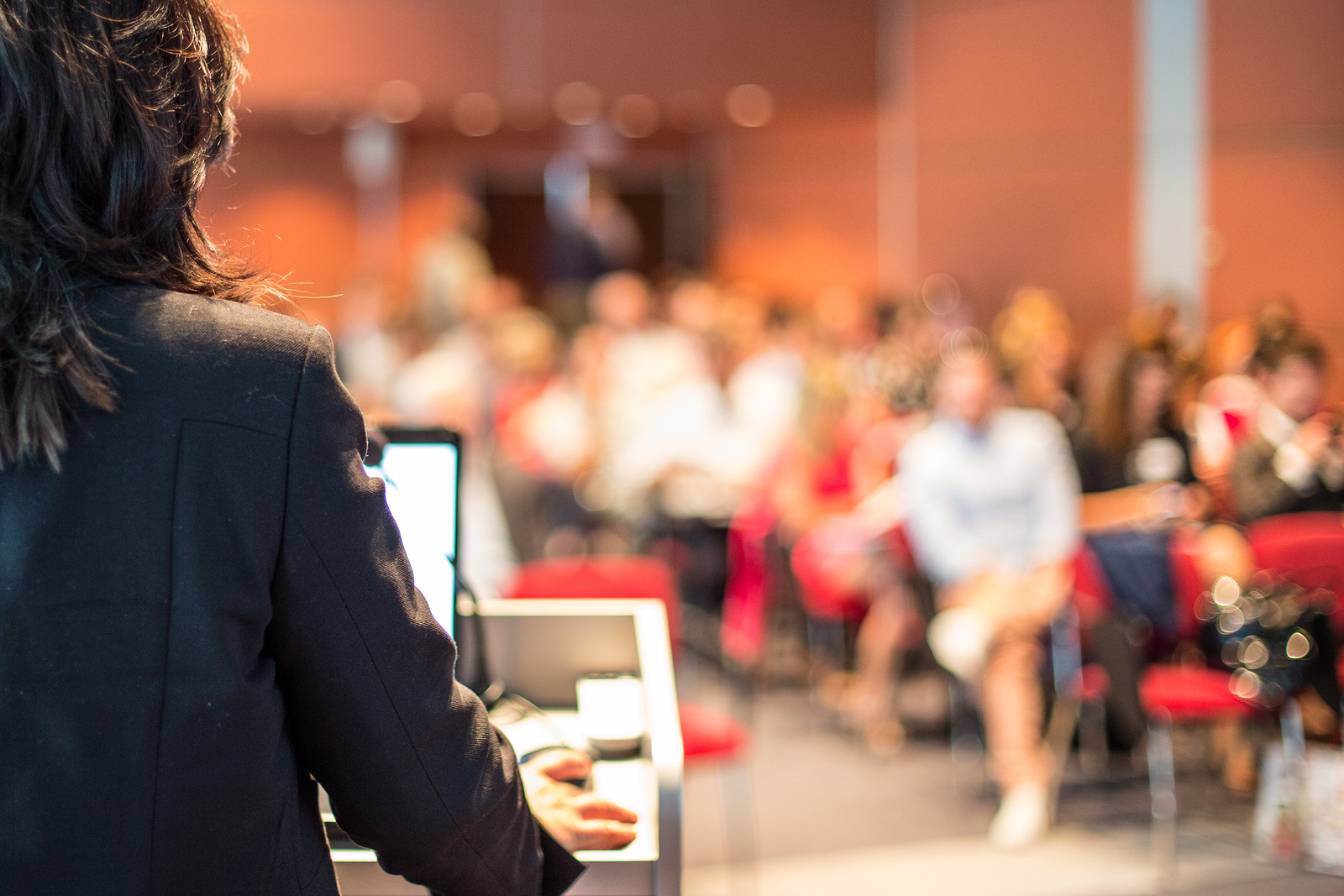Female Public Speaker Giving Talk At Business Event.